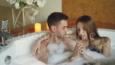 穿着泳衣的年轻人在水疗沙龙的浴缸里交谈、拥抱和触摸手。 浪漫关系